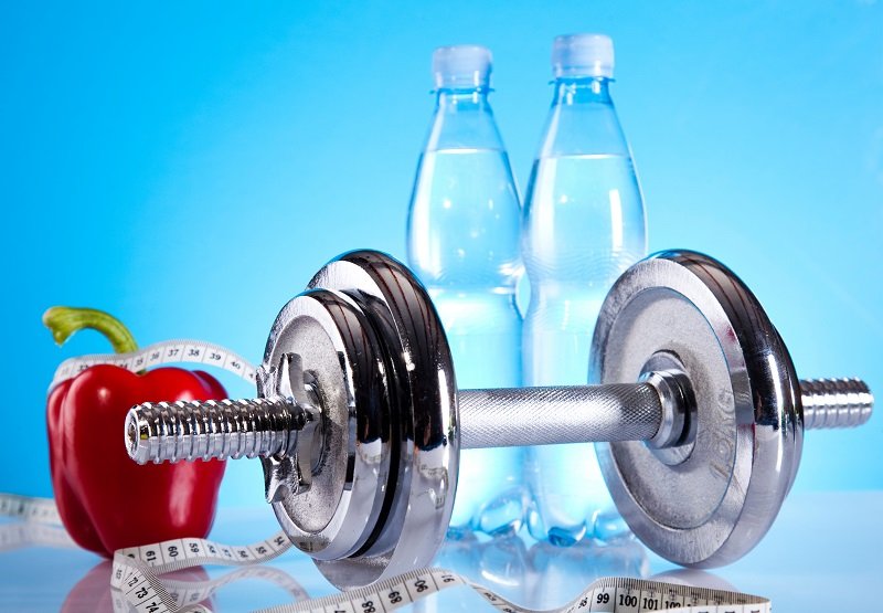 Life Extension, exercise equipment, red bel pepper, bottles of water, measuring tape with a light blue shiny background